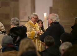 Bischof Dr. Karl-Heinz Wiesemann teilt lächelnd die Kommunion aus